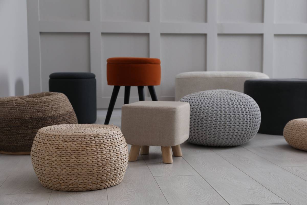 Multiple colorful poufs on display in front of a grey wall