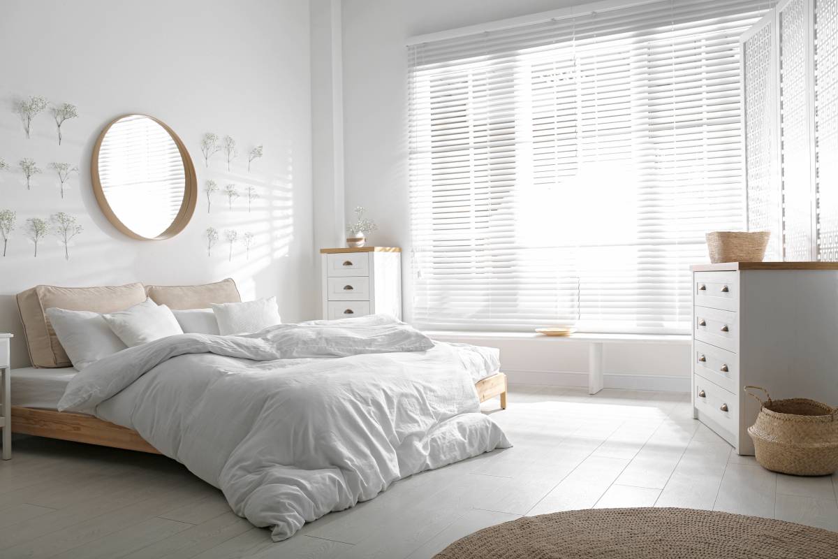 Airy bedroom with wall mirror, two dressers, and king size bed.