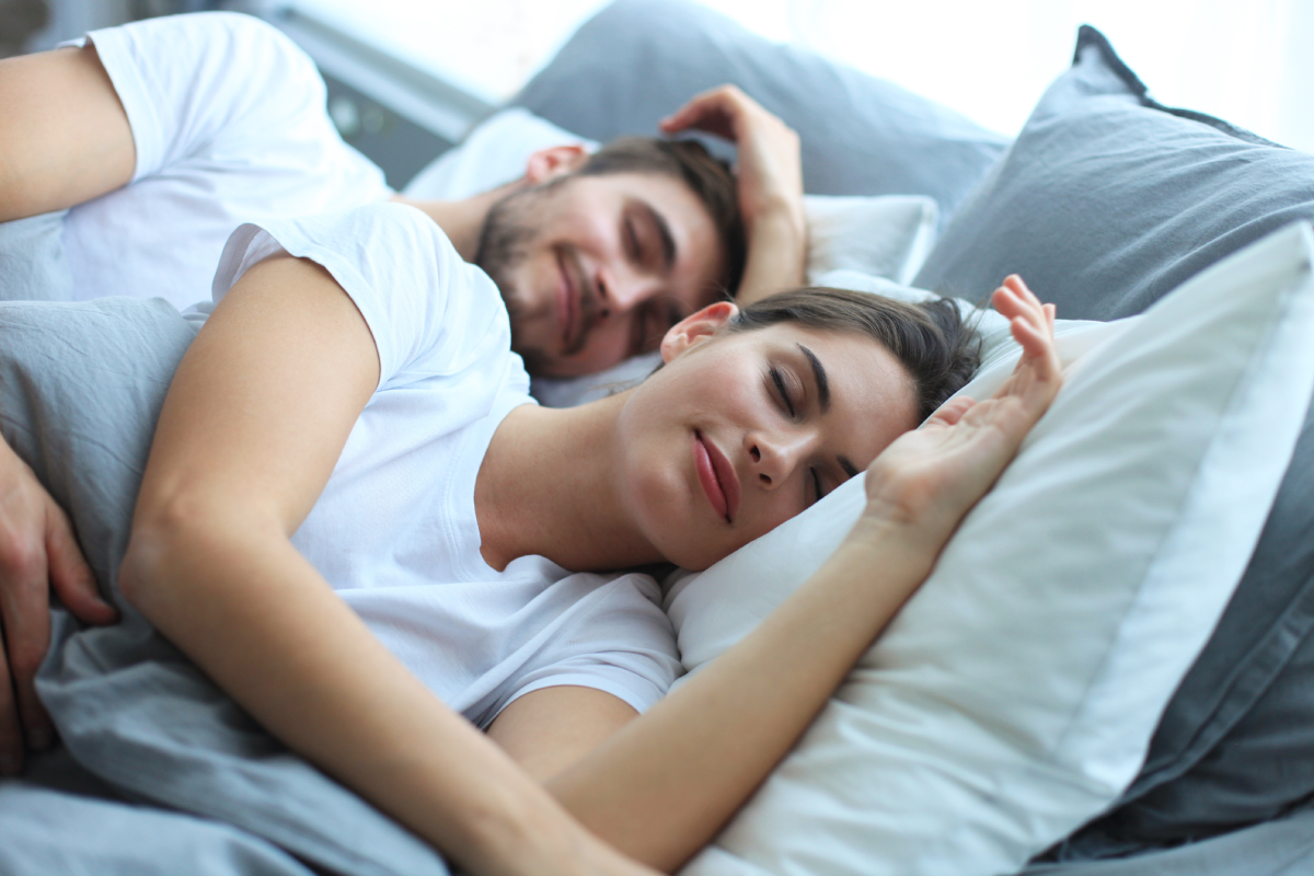 Happy couple sleeping on a mattress with pillows.