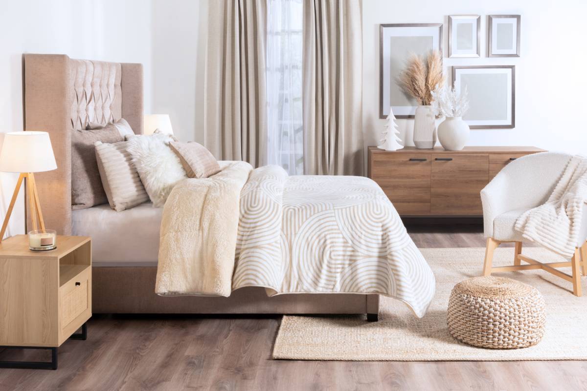 Modern bedroom with upholstered bed, nightstand, dresser, and ottoman.